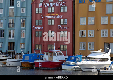 Trondheim boats in front of old wooden timber warehouses wharves on stakes at the river Nid Nidelva Stock Photo