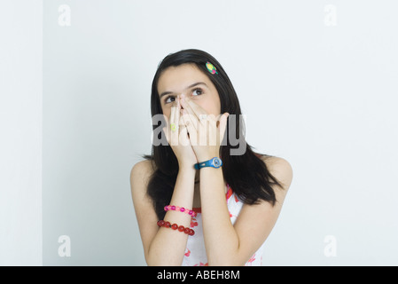 Teenage girl, hands over nose and mouth, looking up, portrait Stock Photo