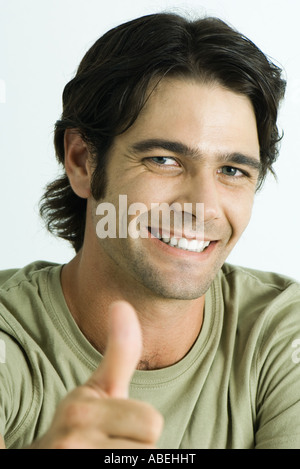 Man smiling at camera, giving thumbs up signal, head and shoulders, portrait Stock Photo