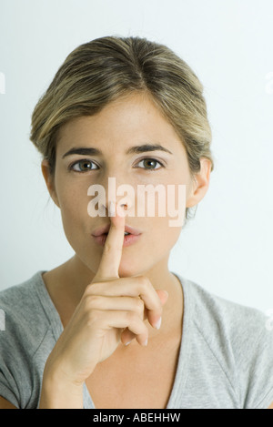 Woman with finger over lips, head and shoulders, portrait Stock Photo