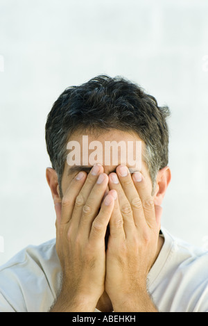 Man covering face with hands, head and shoulders, portrait Stock Photo