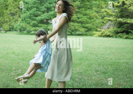 Woman swinging daughter around on grass Stock Photo