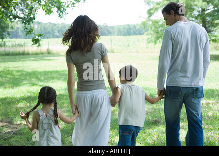 Family walking across lawn on a sunny day, rear view Stock Photo