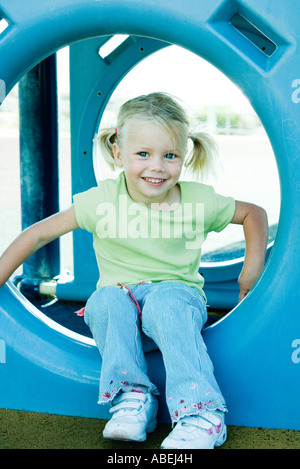 Girl sitting in playground equipment Stock Photo