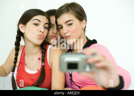 Three young female friends puckering as one takes photo with digital camera Stock Photo
