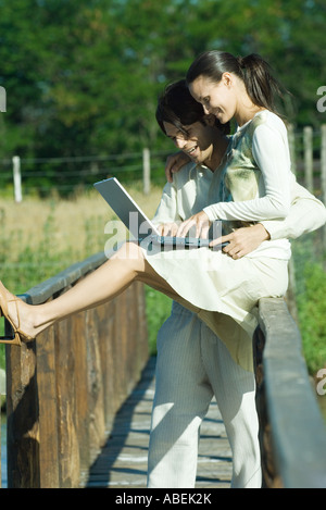 Couple on footbridge using laptop Stock Photo