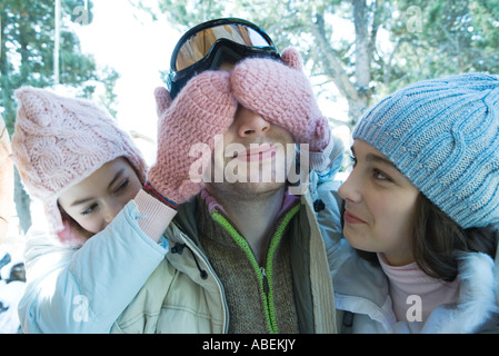 Teen girls with young man, one covering his eyes Stock Photo