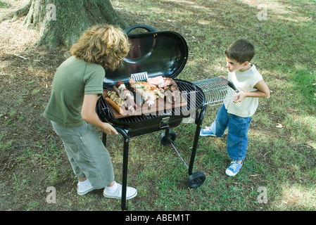 Two boys standing next to tray of grilled meat on barbecue Stock Photo
