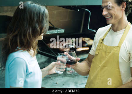 Couple clinking glasses next to barbecue Stock Photo
