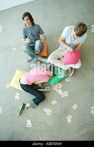 Teen friends with playing cards scattered around them, high angle view Stock Photo