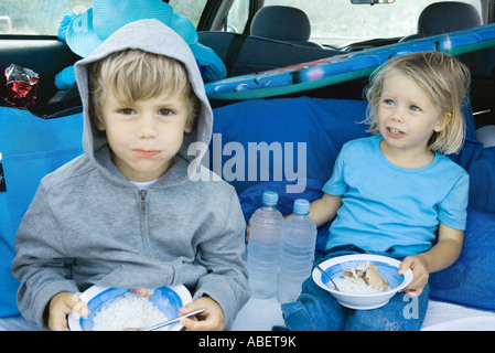 Children eating meal in back of car Stock Photo