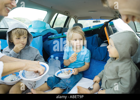 Children eating meal in back of car Stock Photo