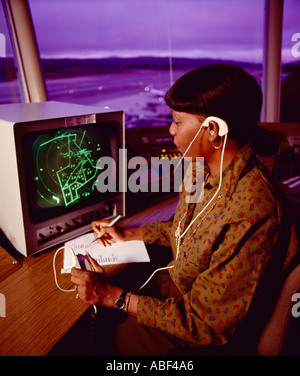 Air Traffic Control - A woman air controller working in an air traffic control ATC tower at an airport at dusk / USA. Stock Photo