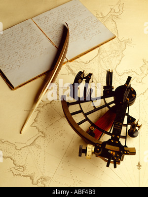 Old historical nautical sextant resting on an old map with a log book and a feather quill pen, in studio. Stock Photo