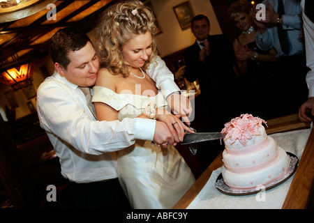 A general view of a newly married bride and groom cutting a wedding cake at their reception Stock Photo