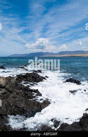 dh  CALETA DE CABALLO LANZAROTE Surf waves breaking on lava rocks El Risco de Famara sea cliffs and bay Stock Photo