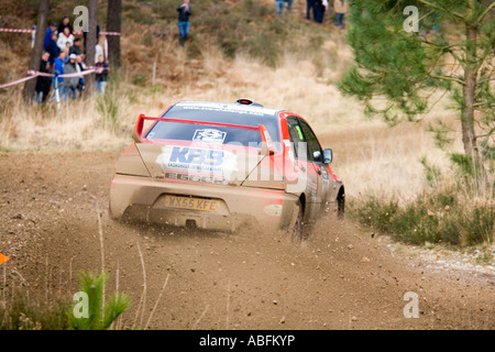 Red Mitsubishi EVO rally car driving action spraying gravel stones dirt and mud as it turns a corner Stock Photo