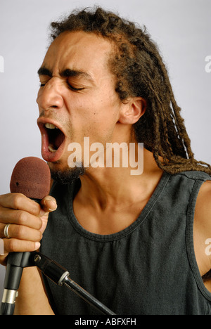 Young black man holding a microphone and singing loudly Stock Photo