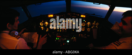 JET AIRCRAFT FLIGHT DECK WITH CREW FLYING TOWARDS RISING SUN Stock Photo