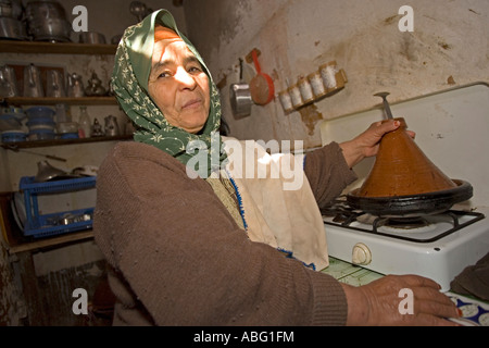 Berber woman cooks using tagine vessel in mudbrick house kitchen old Ait Benhaddou kasbah Morocco Stock Photo
