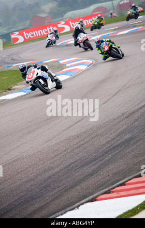 nine racing motorbikes riders leaning through the bends and corners of a chicane Stock Photo
