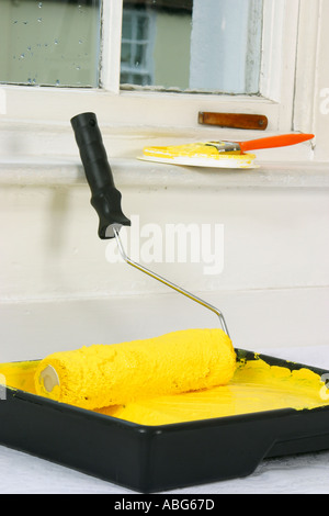 Paint roller and paint tray with paint brush in background on windowsill Stock Photo