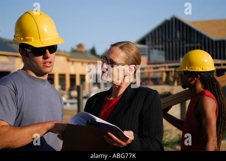 Contractor supervisor explaining progress to the female architect outdoors at the construction site Stock Photo