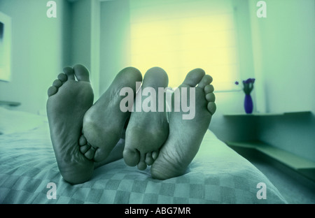 FEET OF COUPLE RESTING IN BED Stock Photo