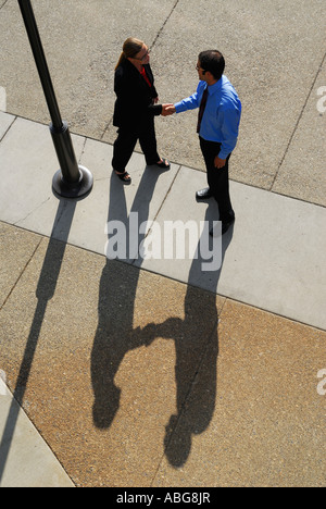 Businessman and woman shadows meeting outdoors in a plaza with a handshake Stock Photo