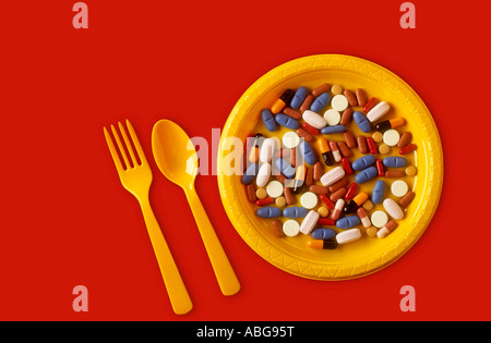 PLASTIC PLATE FILLED WITH MANY DIFFERENT PILLS AND CAPSULES WITH CUTLERY CONCEPT Stock Photo