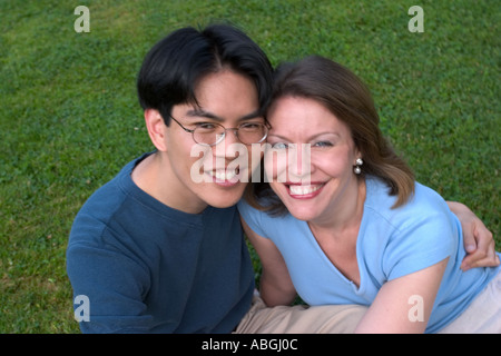 Interracial couple sitting on a lawn in a park Stock Photo