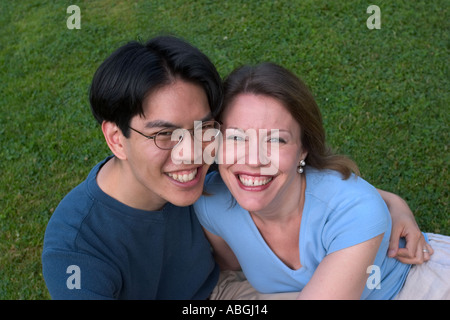 Interracial couple sitting on a lawn in a park Stock Photo