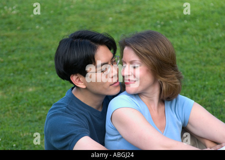 Interracial couple sitting on a lawn in a park Stock Photo