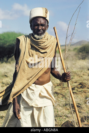 Old Gabbra man holding a wooden stick spear silhouetted against a blue sky Stock Photo