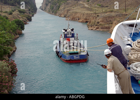 Bow view onboard cruise ship liner crew supervising passage along  narrow Corinth Canal assisted by tug boat Peloponnese peninsula in southern Greece Stock Photo