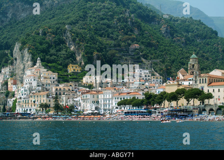 Amalfi town & waterfront buildings historical cathedral bell tower  hillside greenery backdrop beach shoreline view from Tyrrhenian Sea Salerno Italy Stock Photo