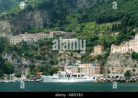 Amalfi town waterfront anchored Falerno sightseeing tour boat in front of UNESCO coastline & hillside buildings at Salerno Campania Southern Italy EU Stock Photo