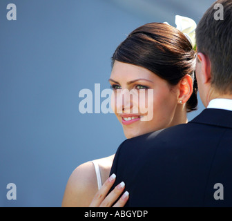 A bride in a traditional white wedding dress seen here looking over her new husbands shoulder. Stock Photo