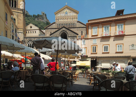 Pediment facade of medieval Amalfi Roman Catholic cathedral steps hidden by outdoor bar cafe parasols in busy Piazza del Duomo Salerno Campania Italy Stock Photo