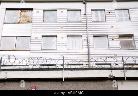 Derelict block of flats boarded up on run down shopping centre with razor wire on Gurnos Estate Merthyr Tydfil South Wales UK Stock Photo