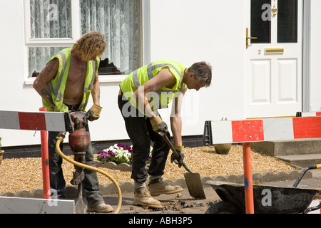 road workers digging a trench to install cables in Stow Road in Ixworth, Suffolk, UK Stock Photo