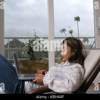 oriental woman lying relaxed using a laptop PC at home balcony view through window Stock Photo