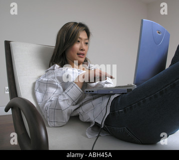 young Asian woman using laptop computer working from home sitting on ...