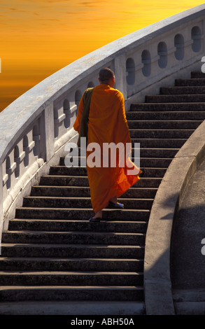 Buddhist monk ascending stone staircase, sunset at Wat Saket temple aka The Golden Mount,  Bangkok, Thailand Stock Photo