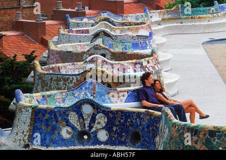 Couple on mosaic tile bench by Antonio Gaudi at Guell Park in Barcelona Spain Stock Photo