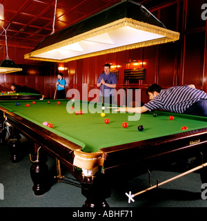 MEN PLAYING SNOOKER IN A WOOD PANELLED ROOM