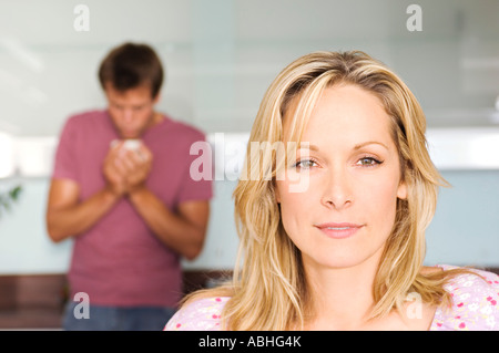 Portrait of a young thoughtful woman, man in background, indoors Stock Photo