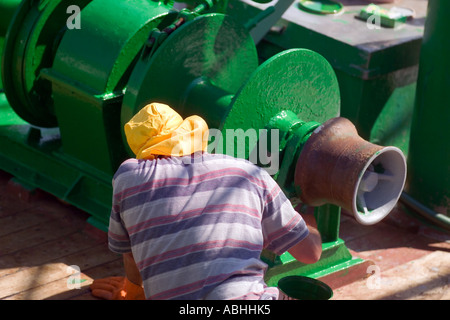 FISHERMAN PAINTING TRAWLER FISHING BOAT'S WINCH WITH GREEN PAINT  ERQUY  HARBOUR BRITTANY FRANCE Stock Photo