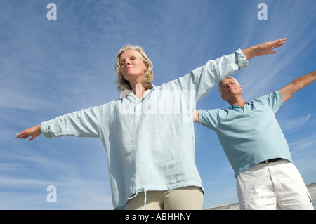 Couple in yoga attitude on the beach, outdoors Stock Photo