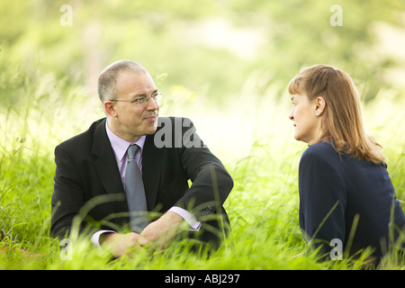 business man and woman meeting in field under shade of a tree Stock Photo